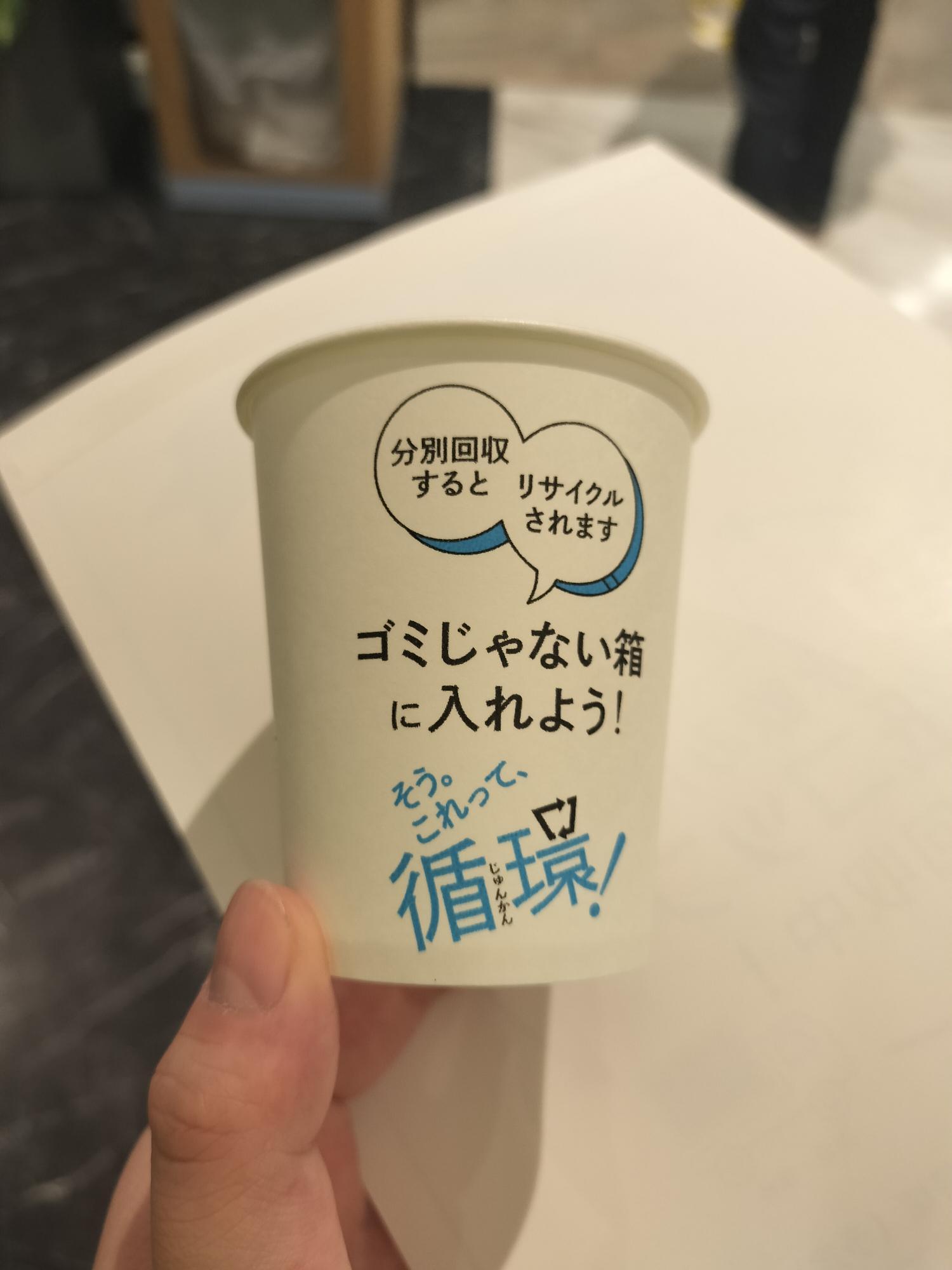 「ゴミじゃない箱に入れよう」と書かれた使用済みの紙コップ